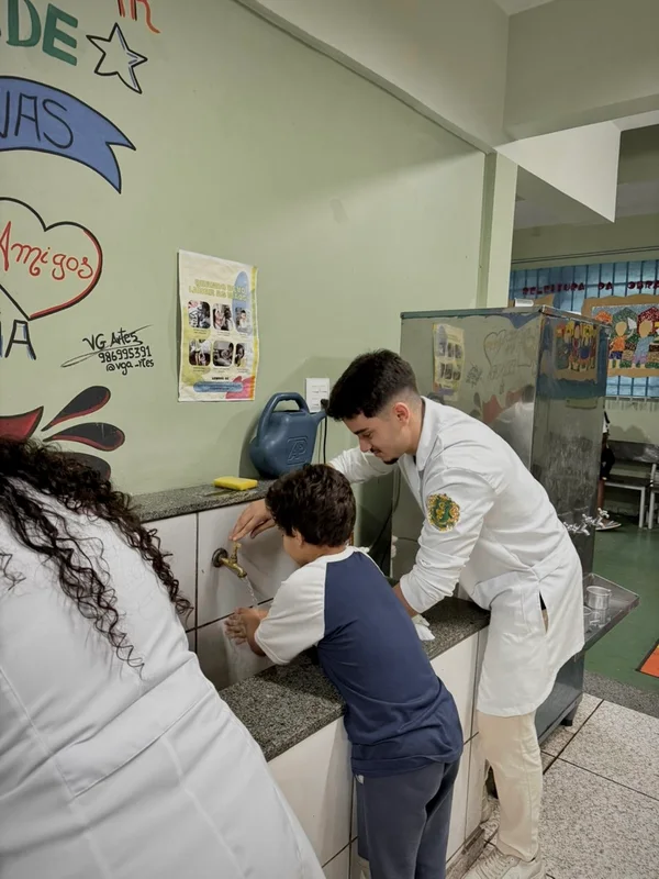 Rafael ensinando uma criança a lavar as mãos numa ação de saúde